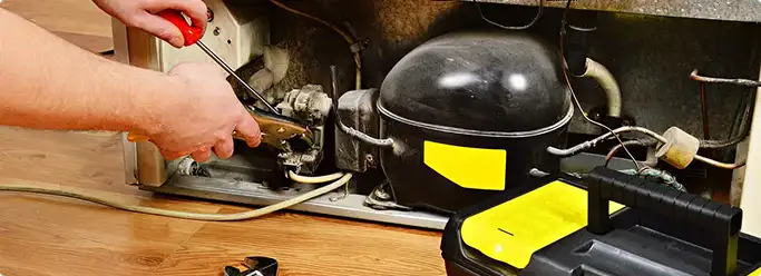 Refrigerator repair technician fixing the compressor and wiring in Chesapeake, VA