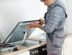 Appliance repair technician installing a built-in cooktop in Norfolk, VA