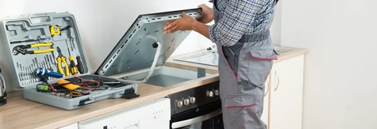 Cooktop repair technician lifting a built-in stovetop for service in Norfolk, VA