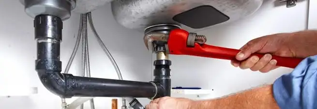Garbage disposal repair technician tightening the sink drain and disposal connection in Norfolk, VA