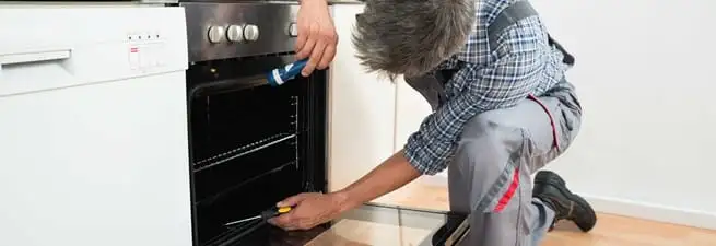 Oven repair technician inspecting and servicing an electric oven in Norfolk, VA