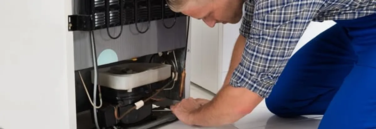 Refrigerator repair technician servicing the compressor and condenser area in Norfolk, VA