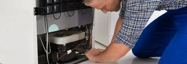 Refrigerator repair technician servicing the compressor and condenser area in Norfolk, VA