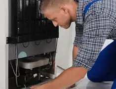 Refrigerator repair technician servicing the compressor and condenser area in Norfolk, VA