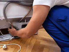 Appliance repair technician fixing refrigerator water line and connections in Norfolk, VA