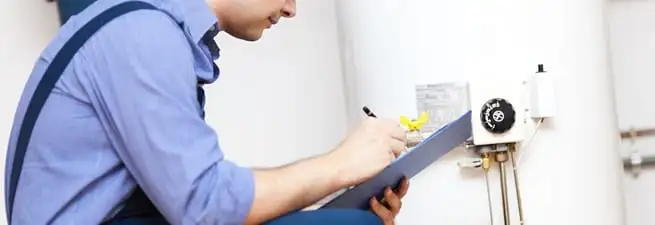 Water heater repair technician inspecting the unit and recording service notes in Norfolk, VA